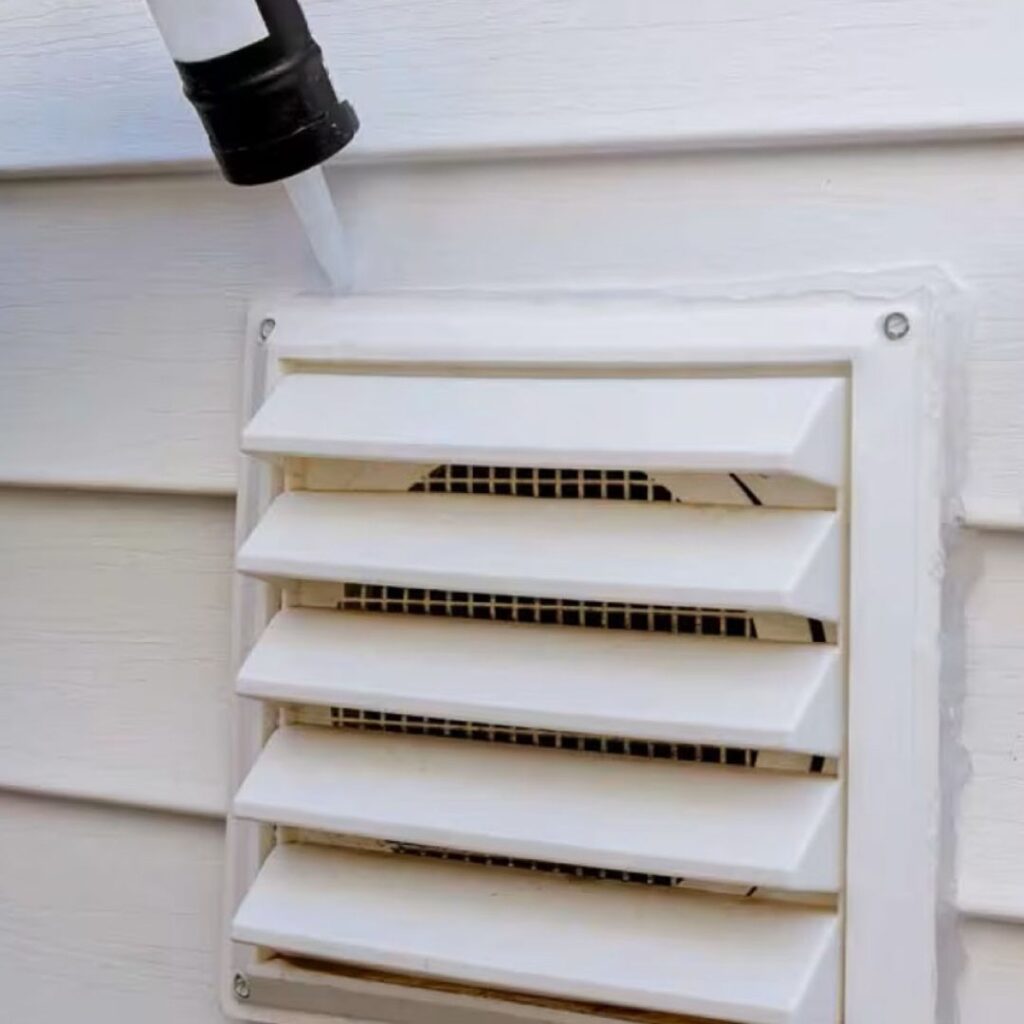 An up-close image of a dryer vent cover being installed or replaced. It is pristine, white, and new.